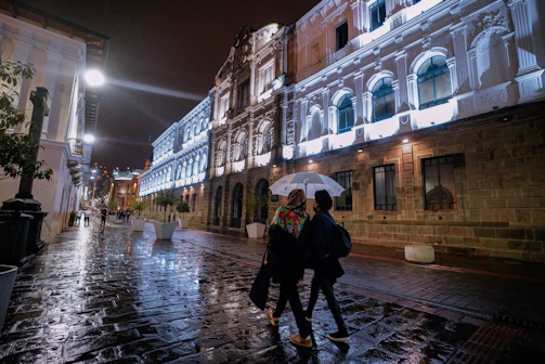 a couple of people walking down a street holding an umbrella
