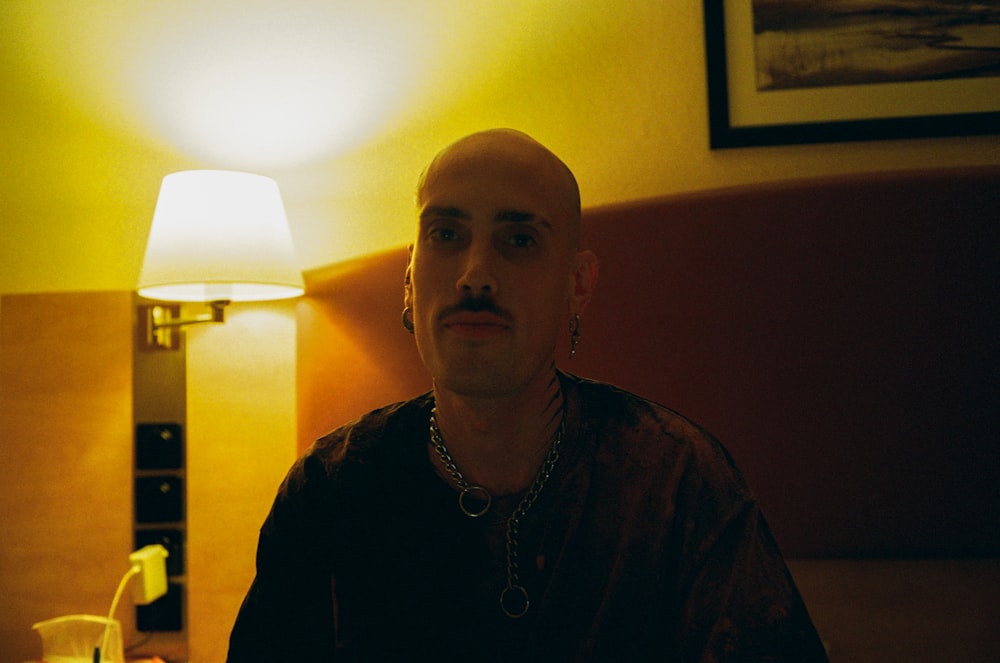a man with a moustache sitting in a hotel room
