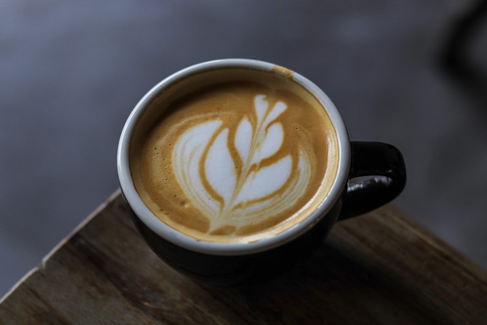 a cup of coffee with a leaf drawn on it