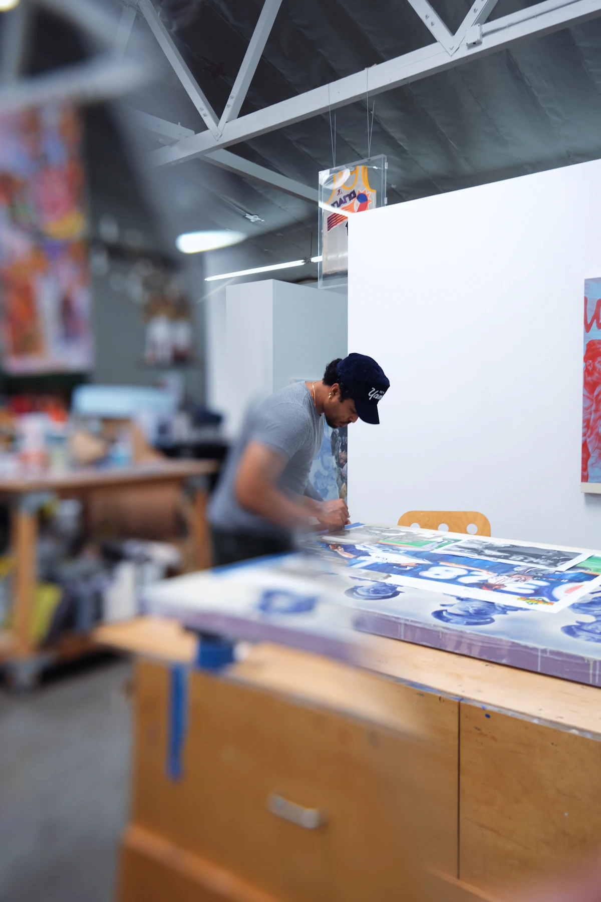 An artist pulling a fresh screen print from a printing press in their studio