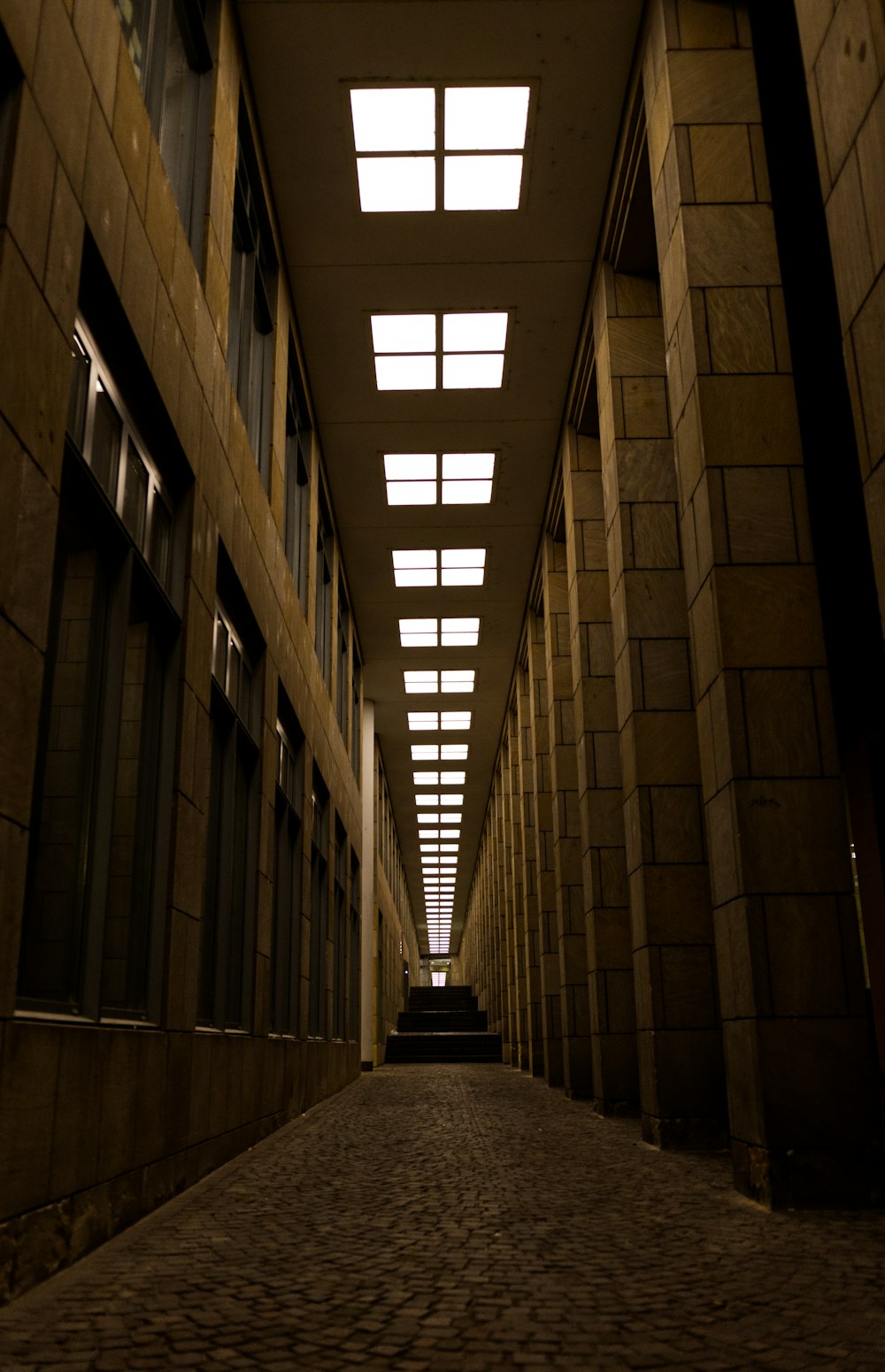 a long hallway with several windows and a brick floor