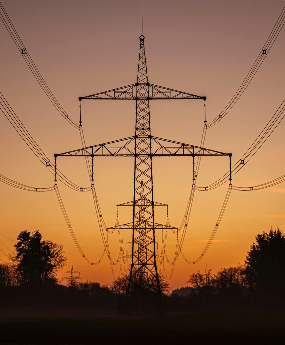 a high voltage power line with the sun setting in the background