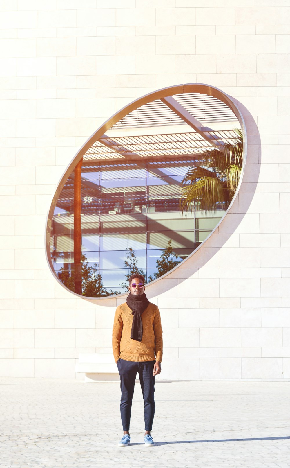 a man standing in front of a large circular mirror