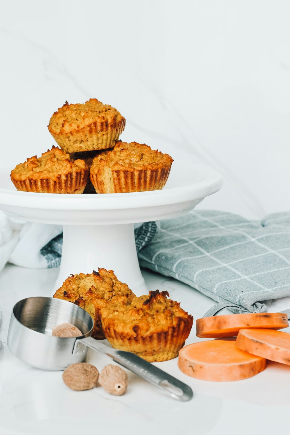 a plate of carrot muffins next to a bowl of carrots