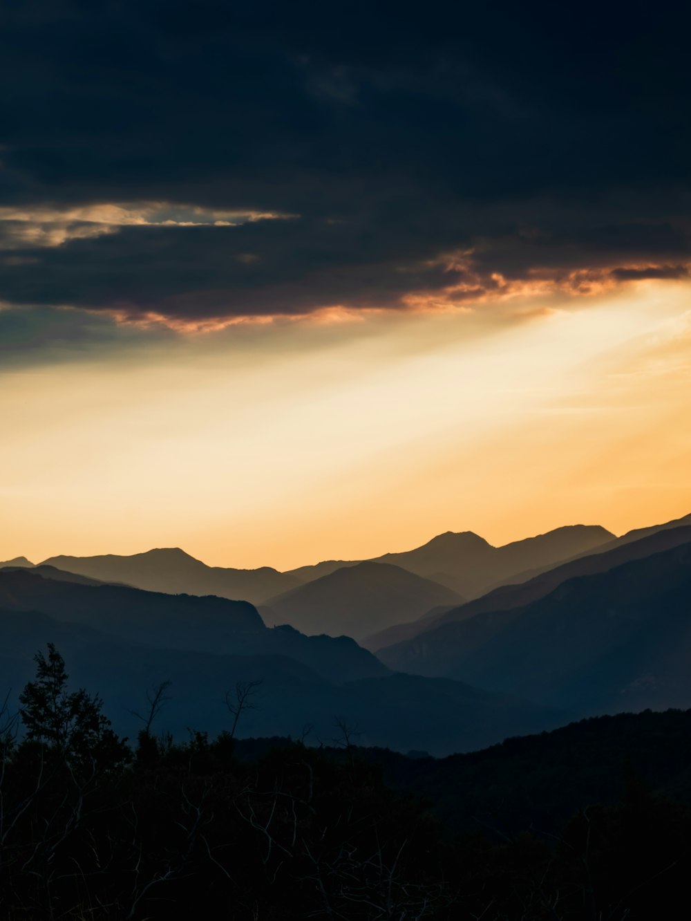 the sun is setting over a mountain range