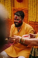 A joyful bride smiling brightly under a shower of yellow turmeric powder.