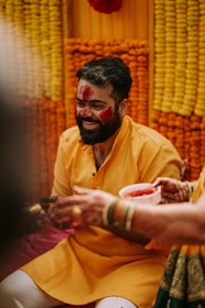 A joyful bride smiling brightly under a shower of yellow turmeric powder.