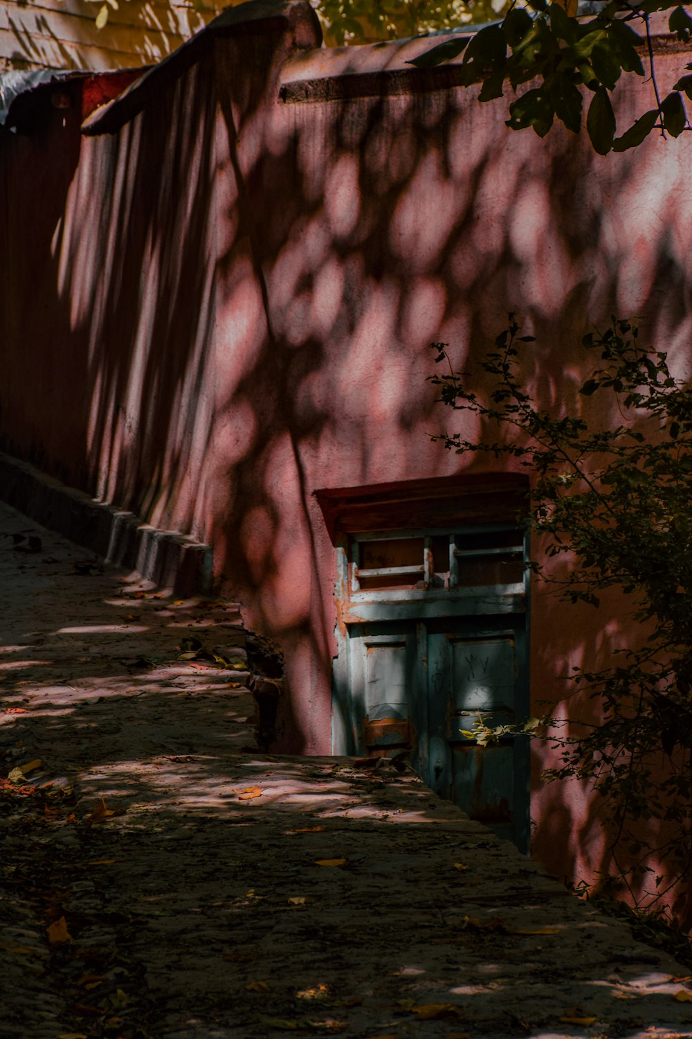 a red building with a green door next to a tree