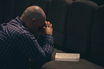a man sitting on a couch with his hands on his face