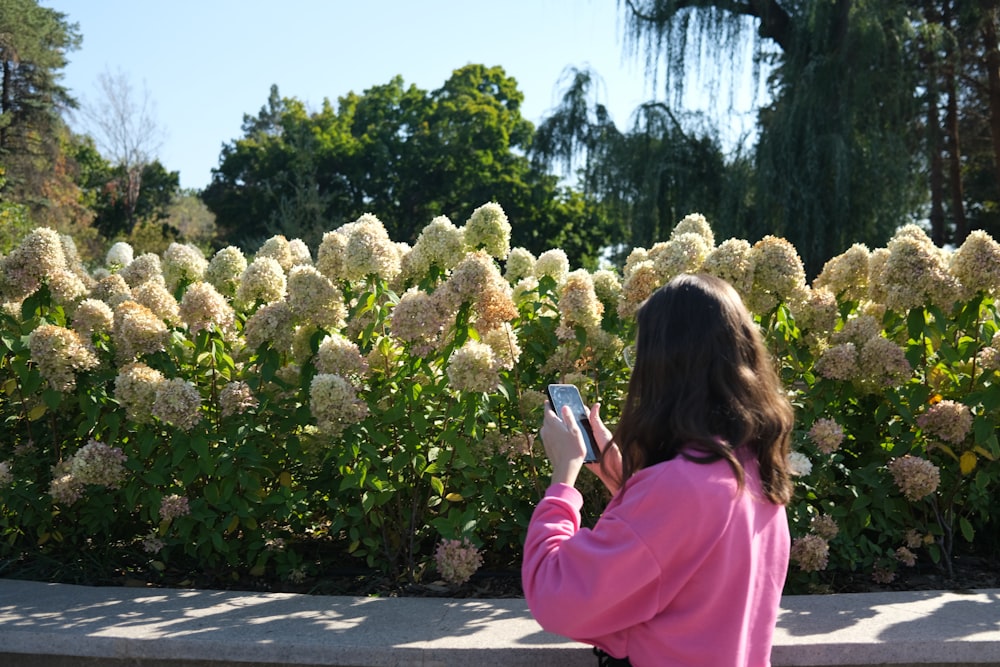 a woman taking a picture of a flower garden