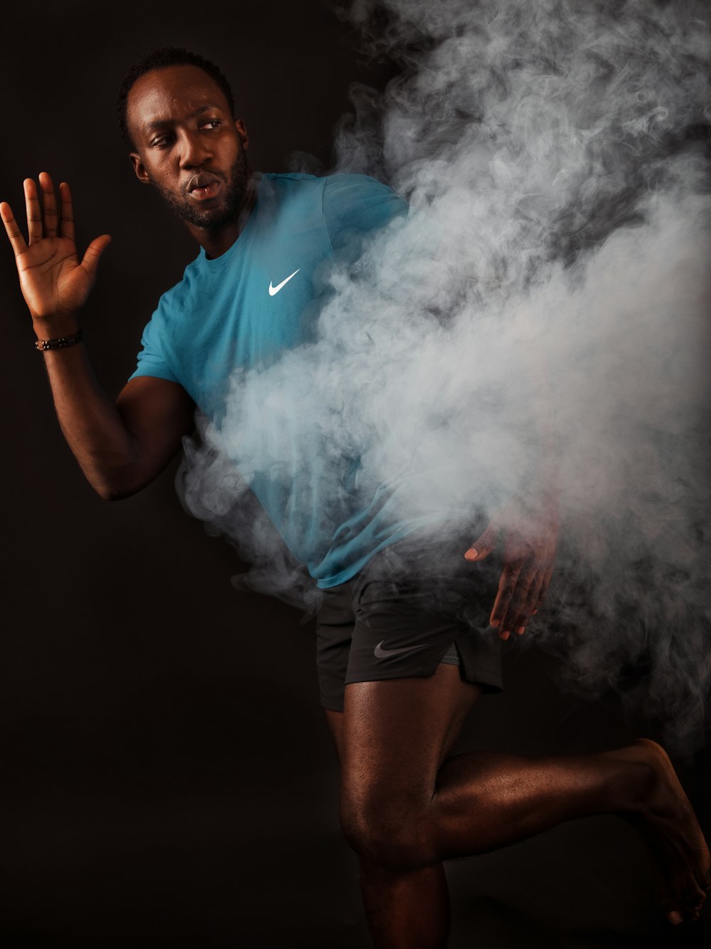 a man in a blue shirt is running through smoke