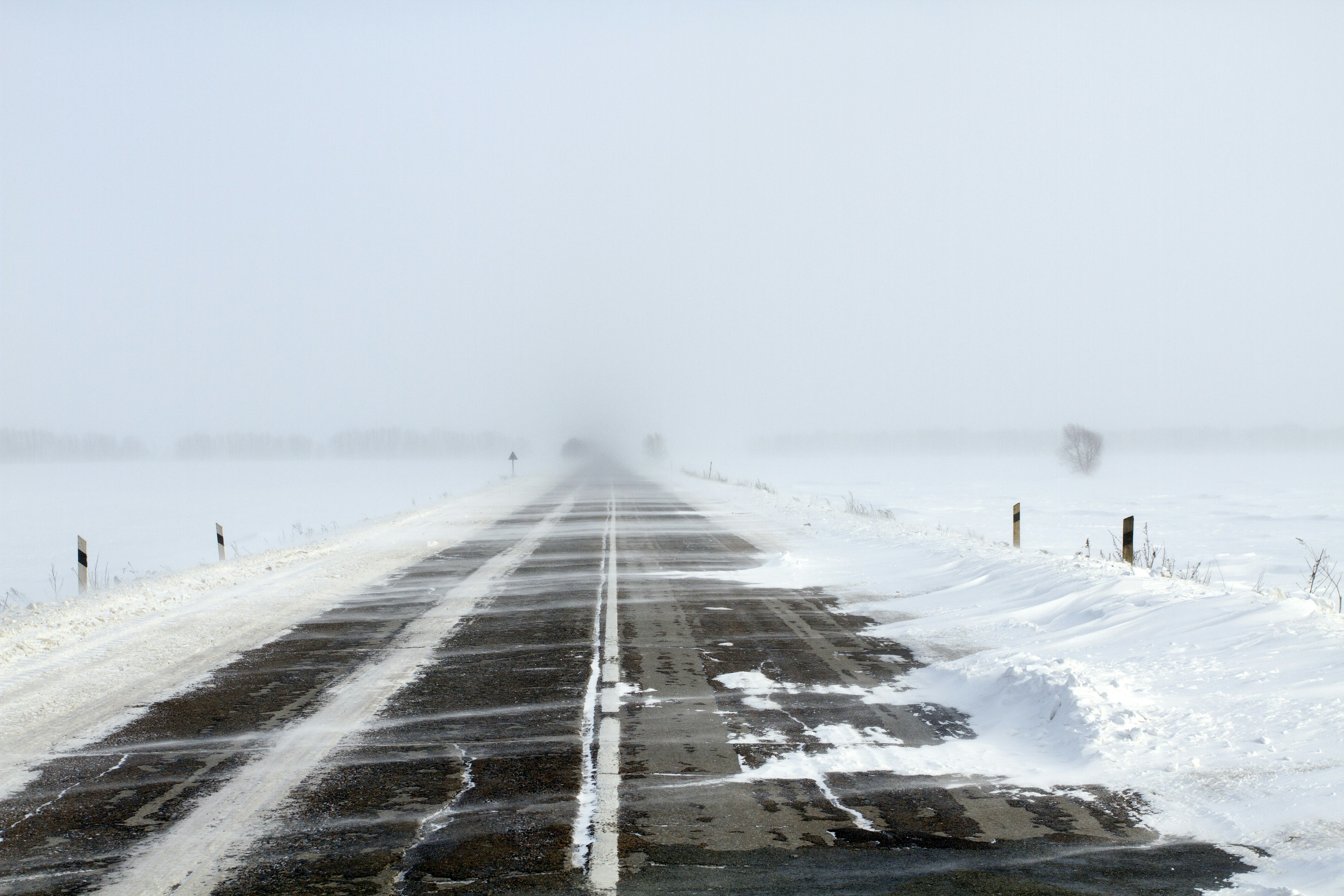 a snow covered road in the middle of nowhere, Snowing road in the middle of snow fields