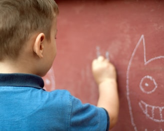 a little boy writing on a wall with a marker