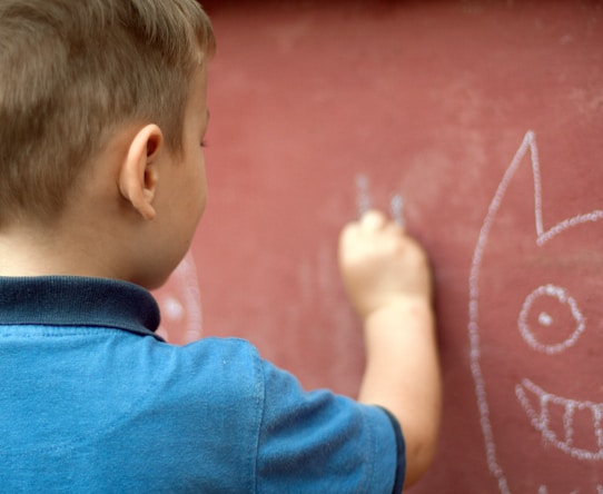 a little boy writing on a wall with a marker