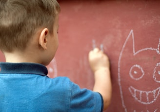 a little boy writing on a wall with a marker