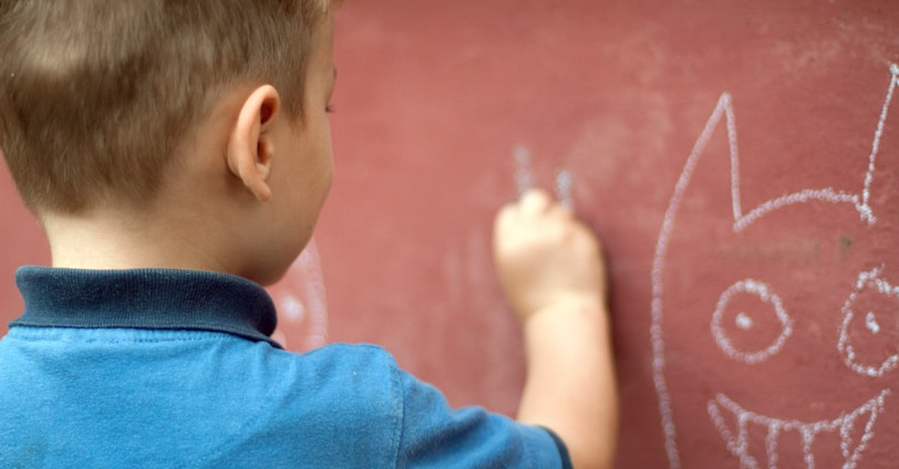 a little boy writing on a wall with a marker
