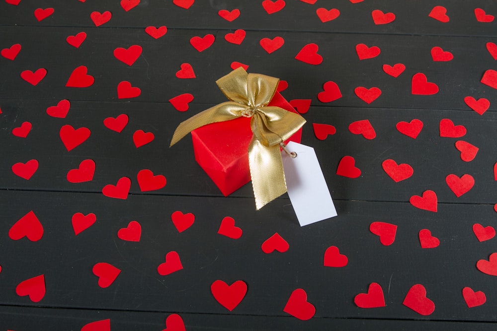 une boîte-cadeau rouge avec un ruban doré et une étiquette dessus