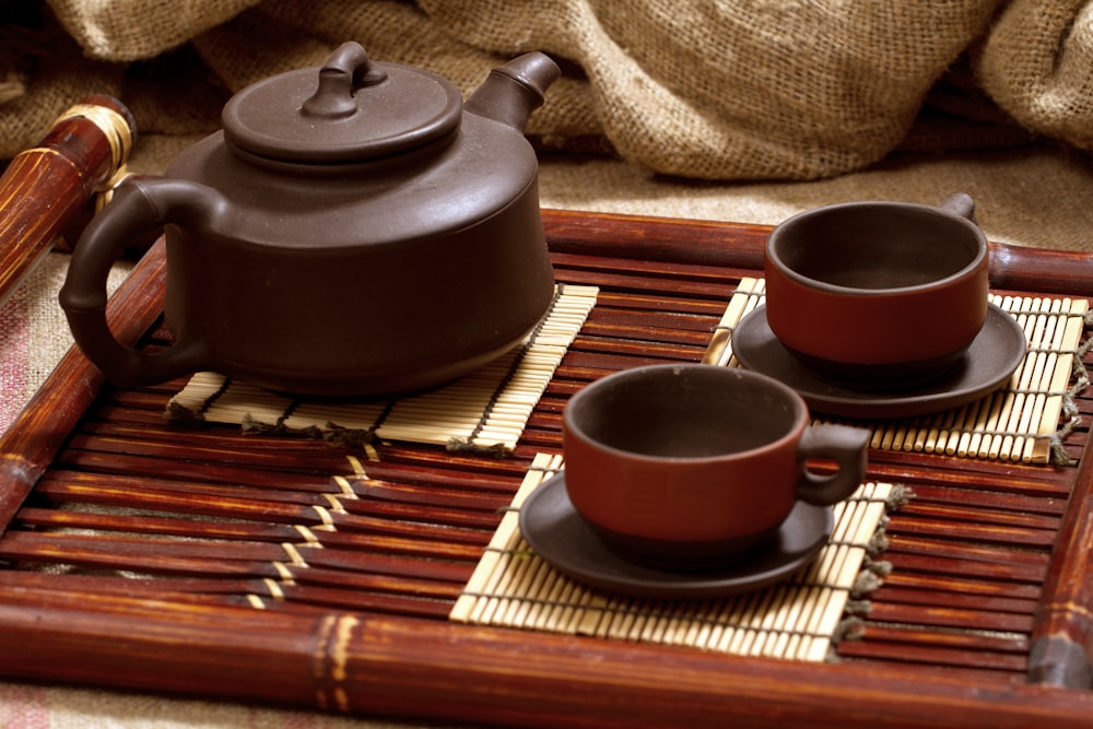 a tray with three cups and a teapot on it