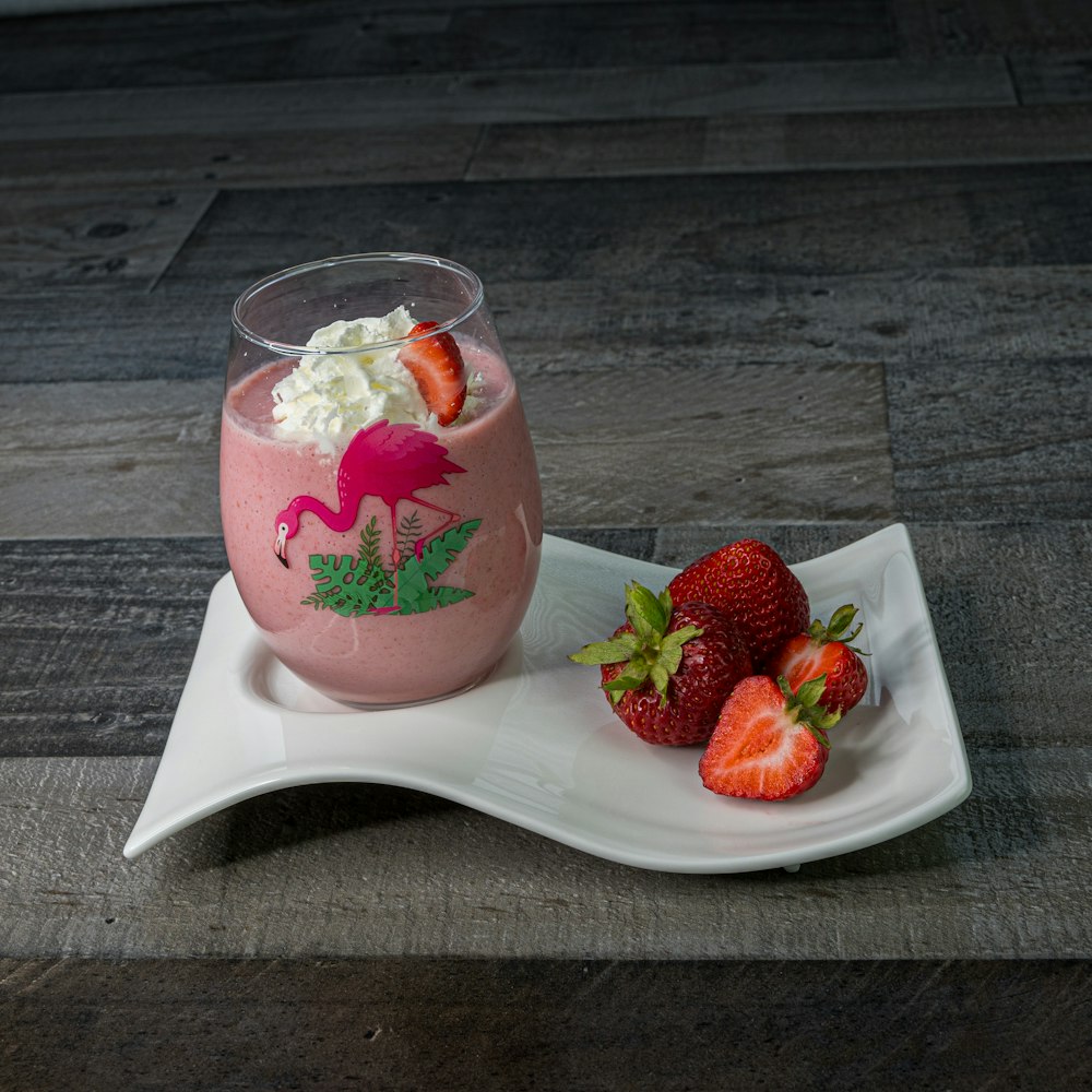 a pink smoothie with strawberries on a plate