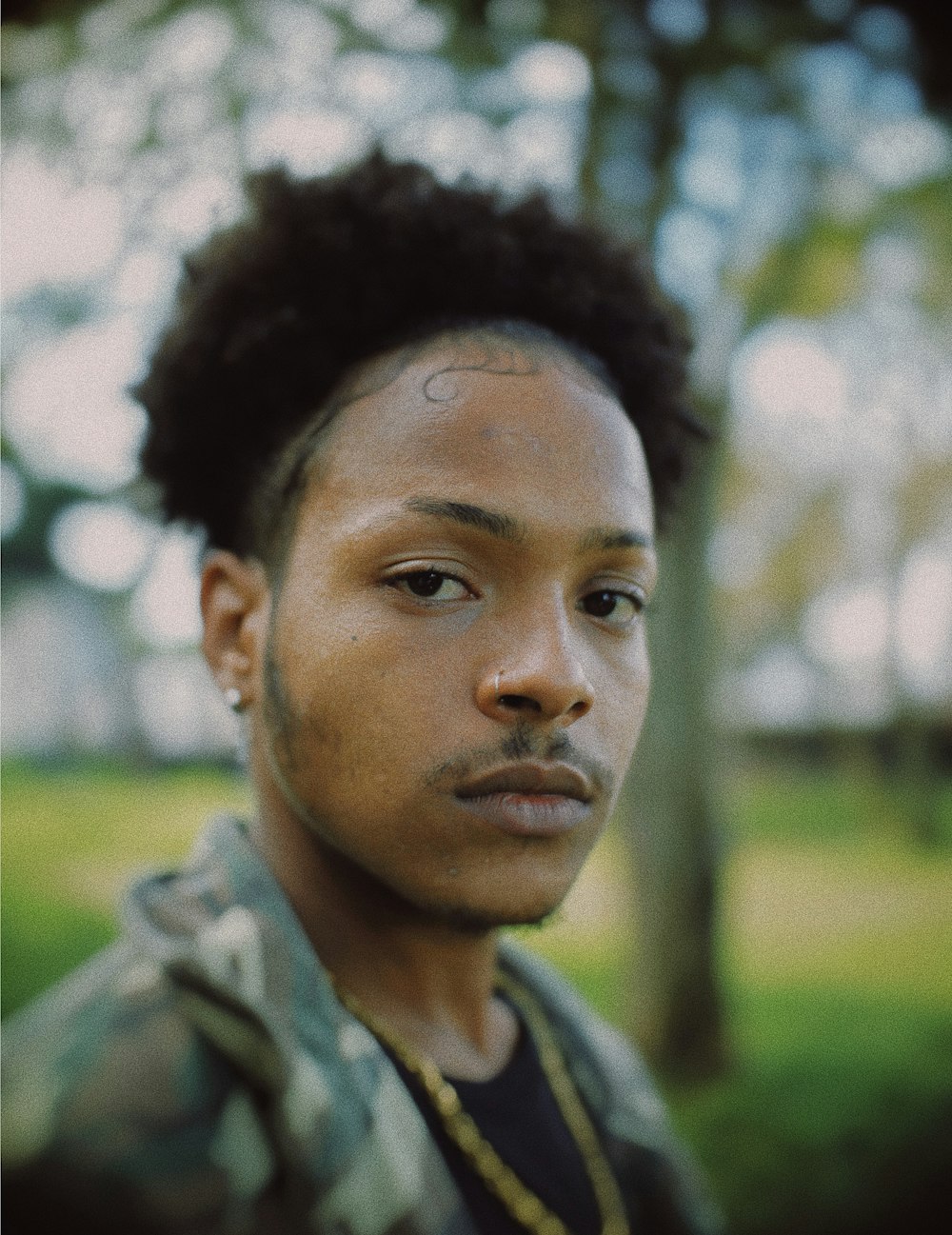 a man with dreadlocks standing in a park