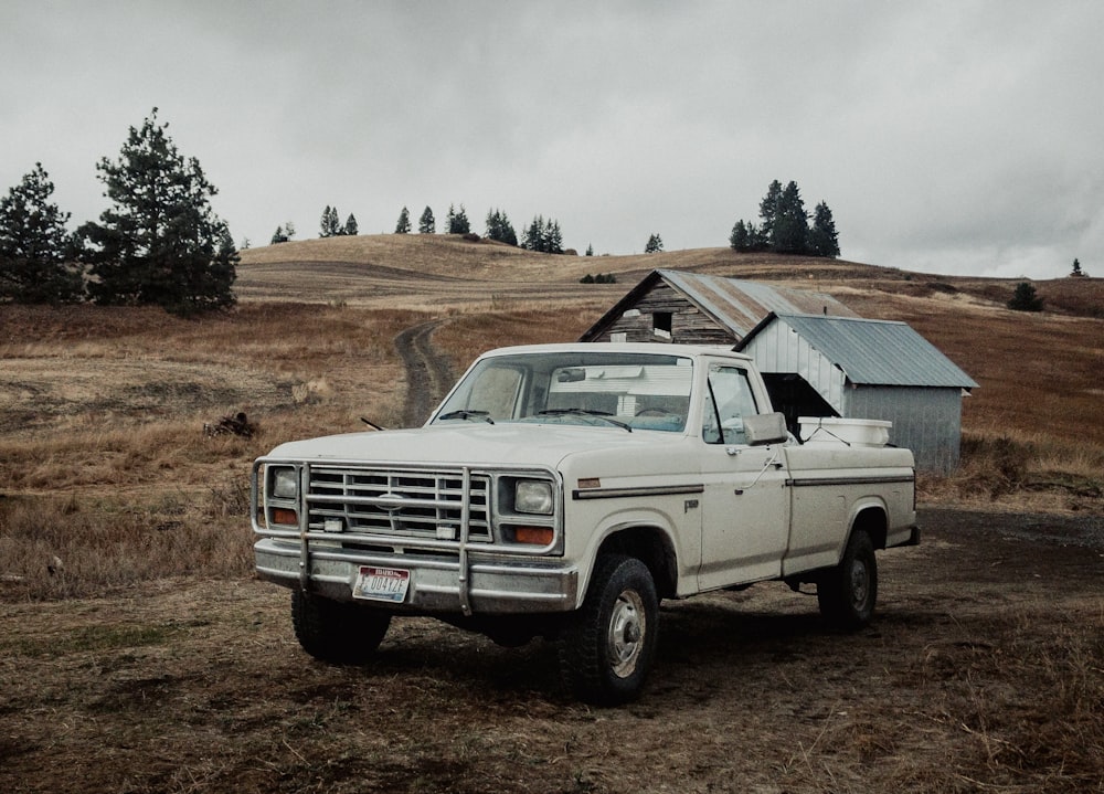 a white truck parked in a field next to a barn