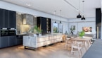 A modern kitchen with sleek, minimalistic design elements, featuring a large marble countertop island with seating, dark cabinetry, and contemporary light fixtures. There are plants and decor items on the island, adding a touch of greenery. The open living area includes a dining table with chairs and a cozy seating space, creating an inviting and functional atmosphere.