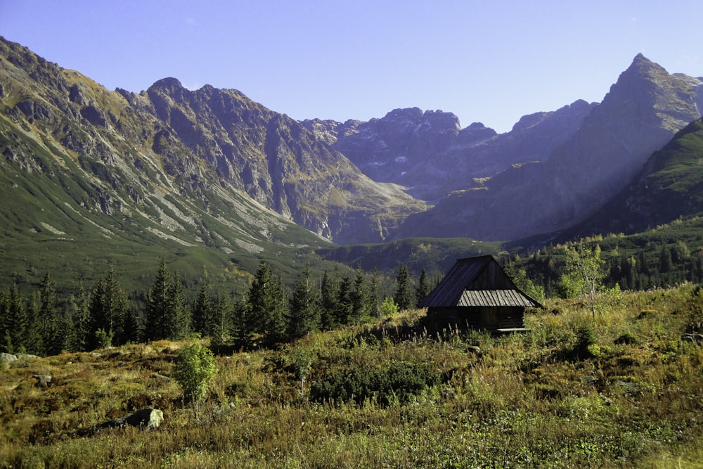 a small cabin in the middle of a mountain range