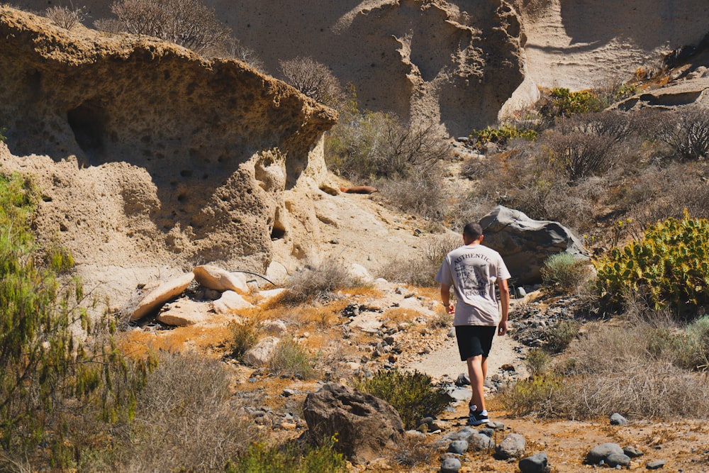 a man walking down a trail in the desert