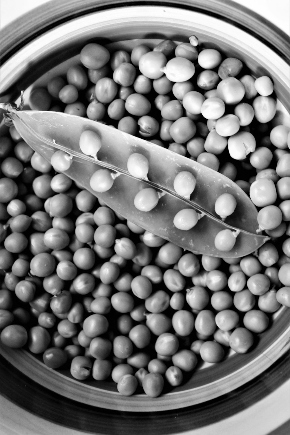 black and white photograph of peas in a bowl