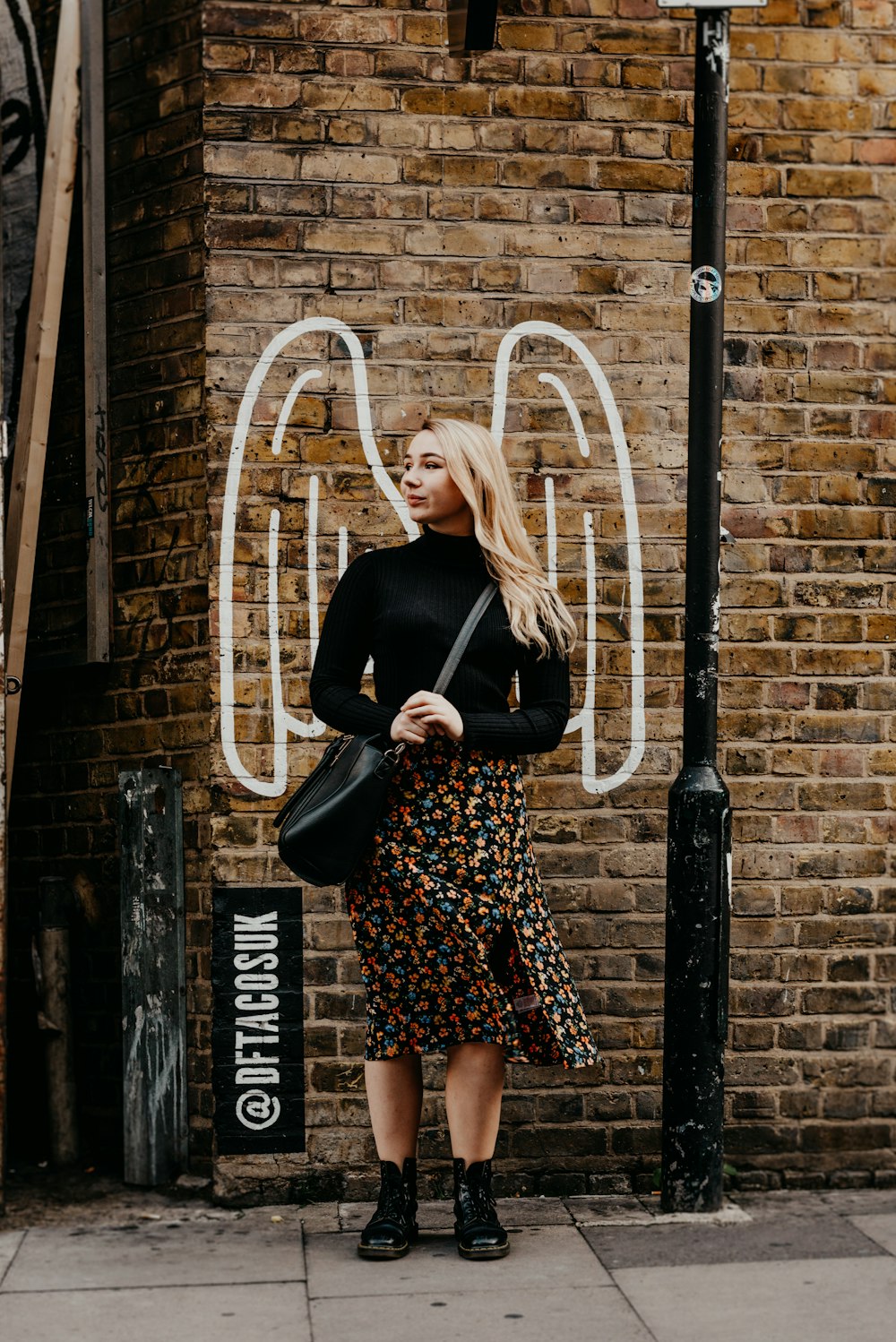 a woman standing in front of a brick wall