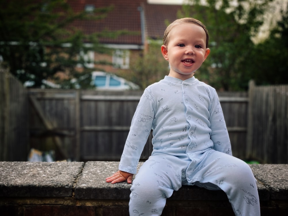 a little boy that is sitting on a wall