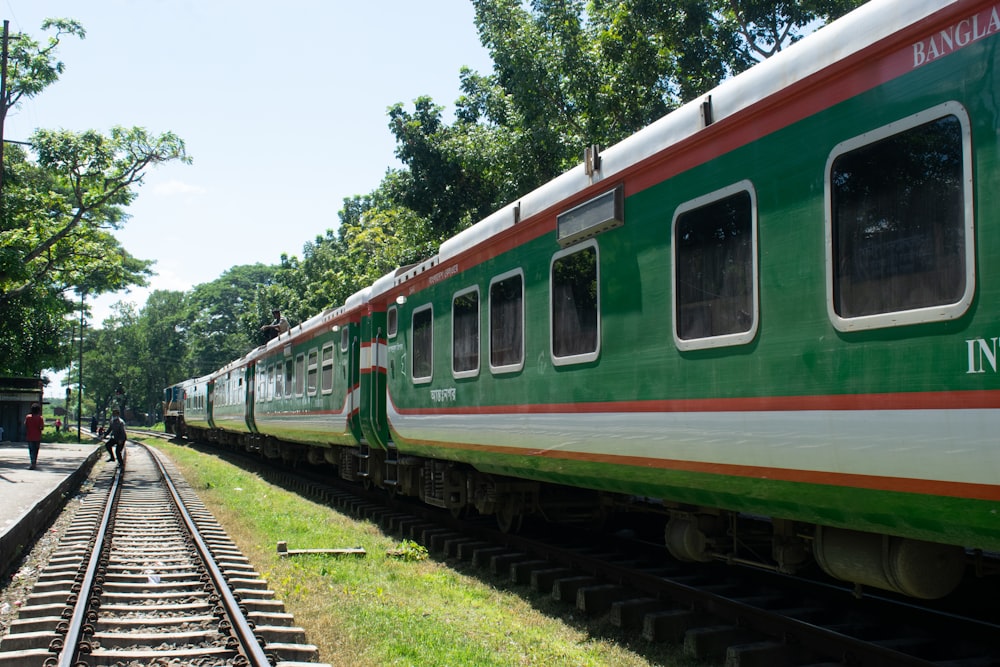 a green and white train traveling down train tracks