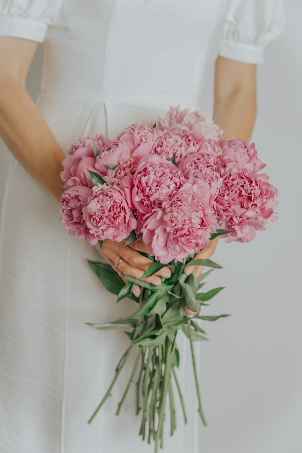 a woman in a white dress holding a bouquet of pink flowers