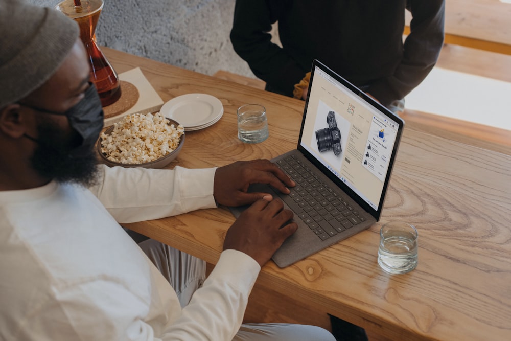 Person sitting on a table on Surface laptop wearing a mask 