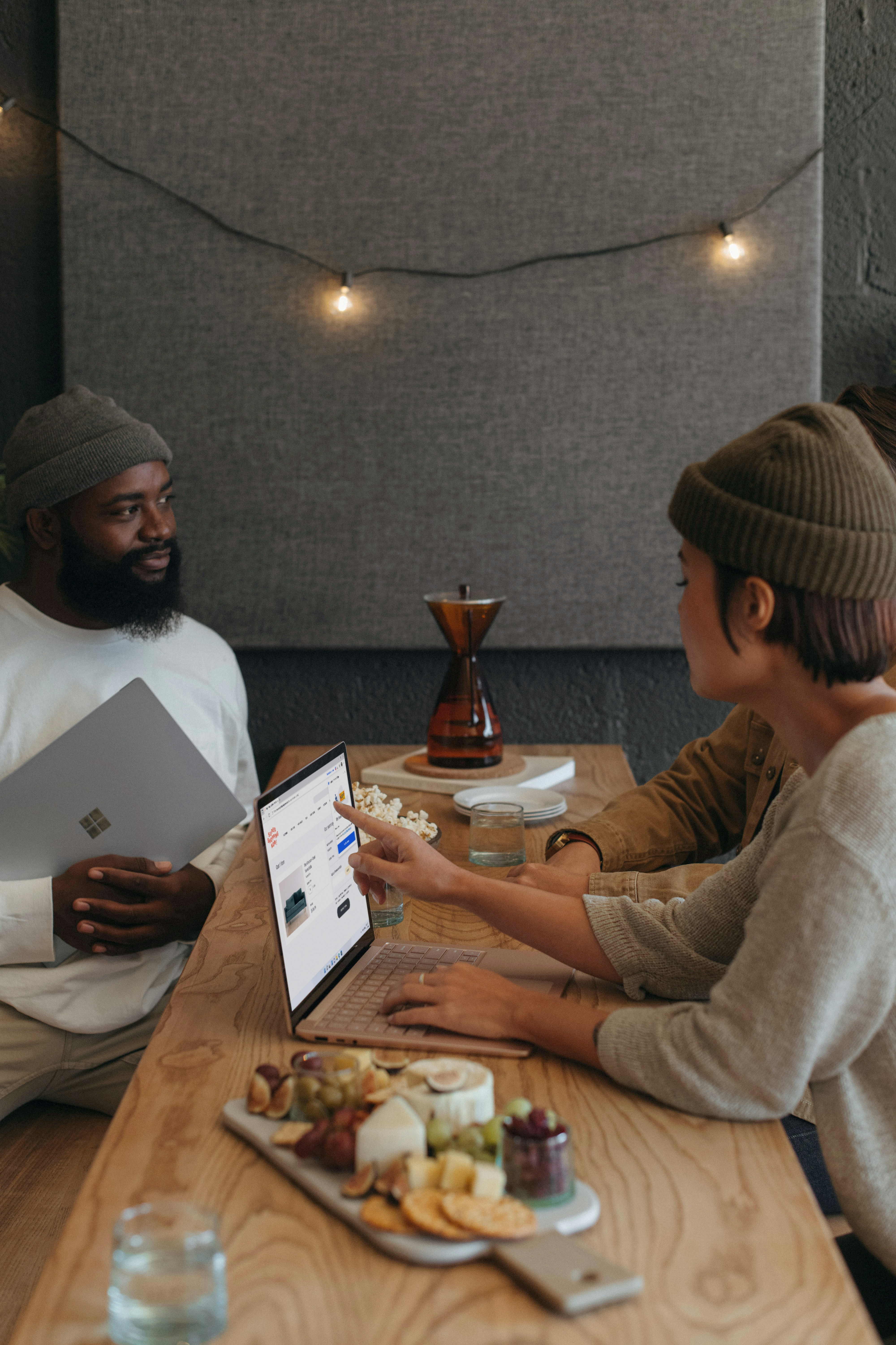 Two coworkers sitting in an office working on Surface laptops holiday platter and decorations surrounding them