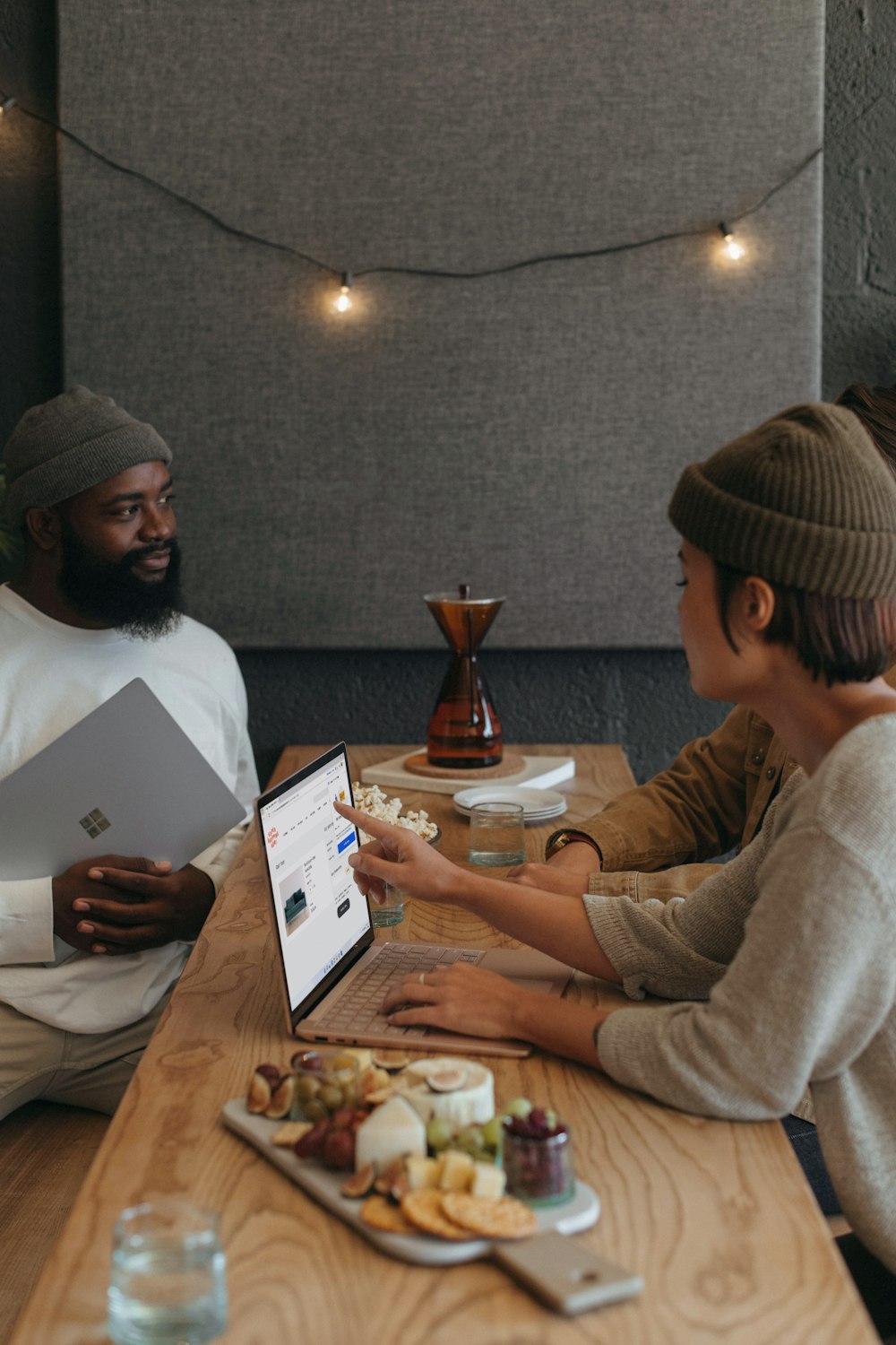 オフィスに座って Surface ノート PC のホリデー プラッターとそれを取り巻く装飾品に取り組んでいる 2 人の同僚