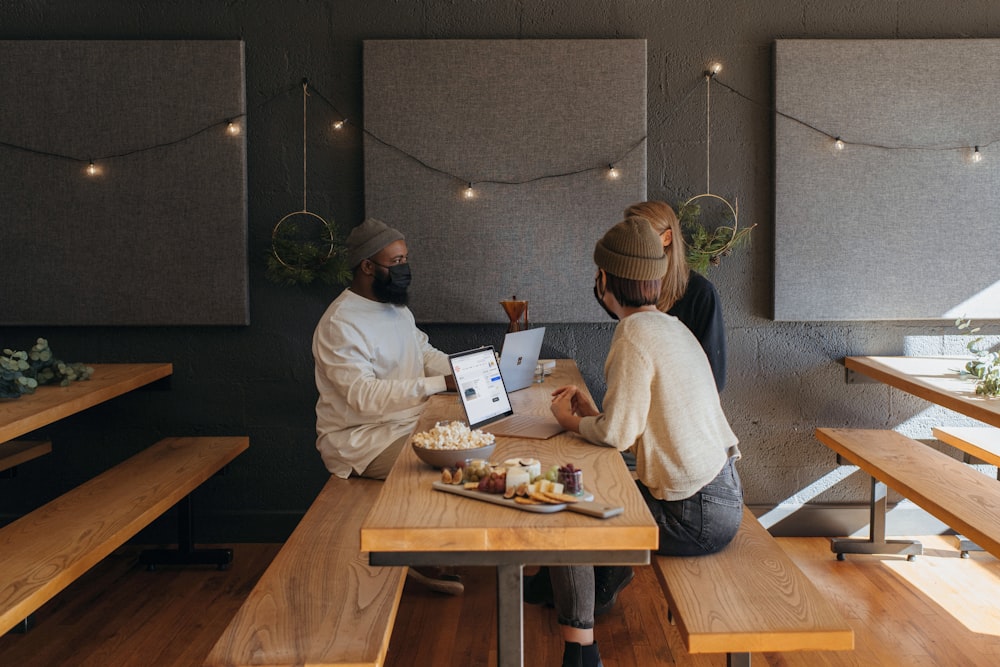 Three people surrounding a table at work wearing masks on their Surface laptops 