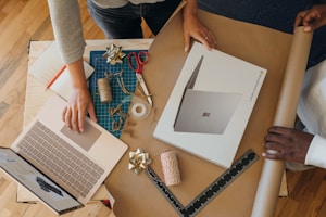 Microsoft: Overhead view of person wrapping a surface laptop box while clicking on a surface laptop