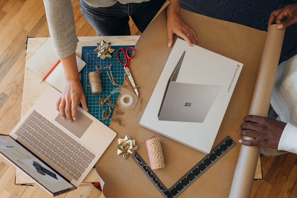 Vista aérea de una persona envolviendo una caja de Surface Laptop mientras hace clic en una Surface Laptop