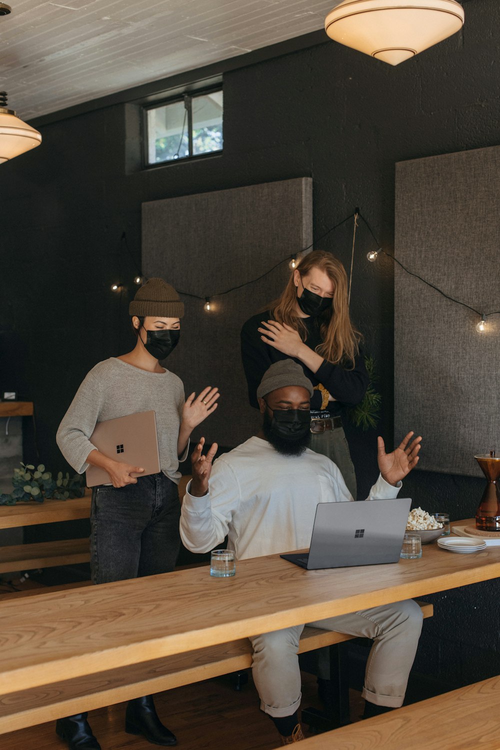 Three coworkers wearing masks talking with someone on video chat in an office