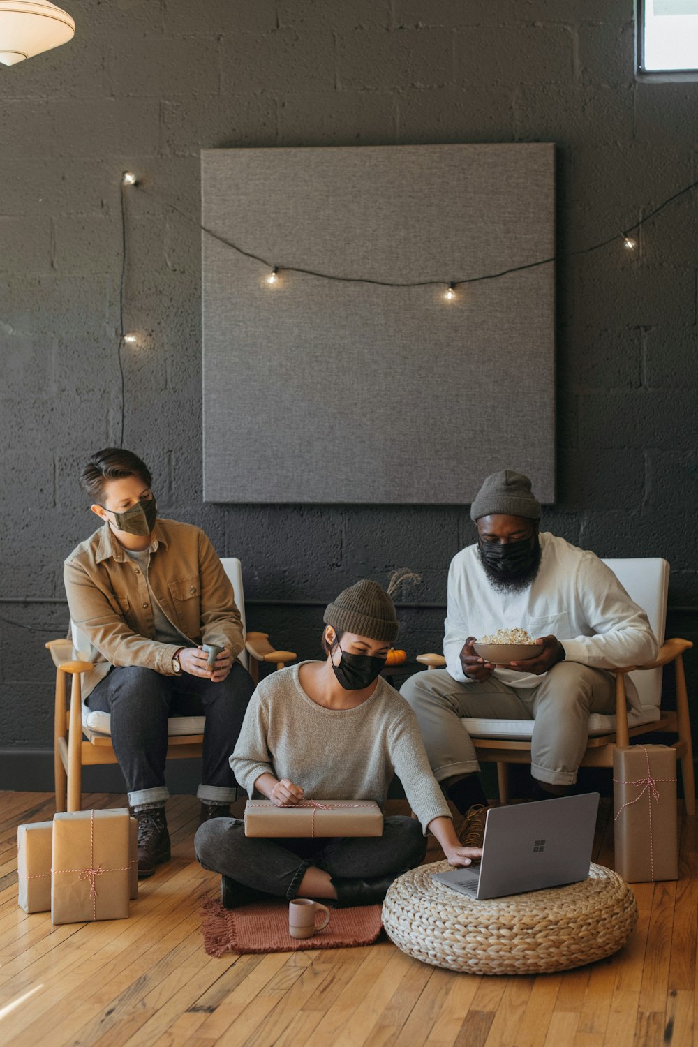 Three coworkers wearing masks on a Surface laptop with Christmas presents on a cart 