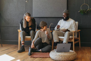 Three coworkers sitting together laughing Surface laptop on furniture 