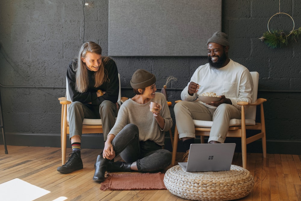 Three coworkers sitting together laughing Surface laptop on furniture 