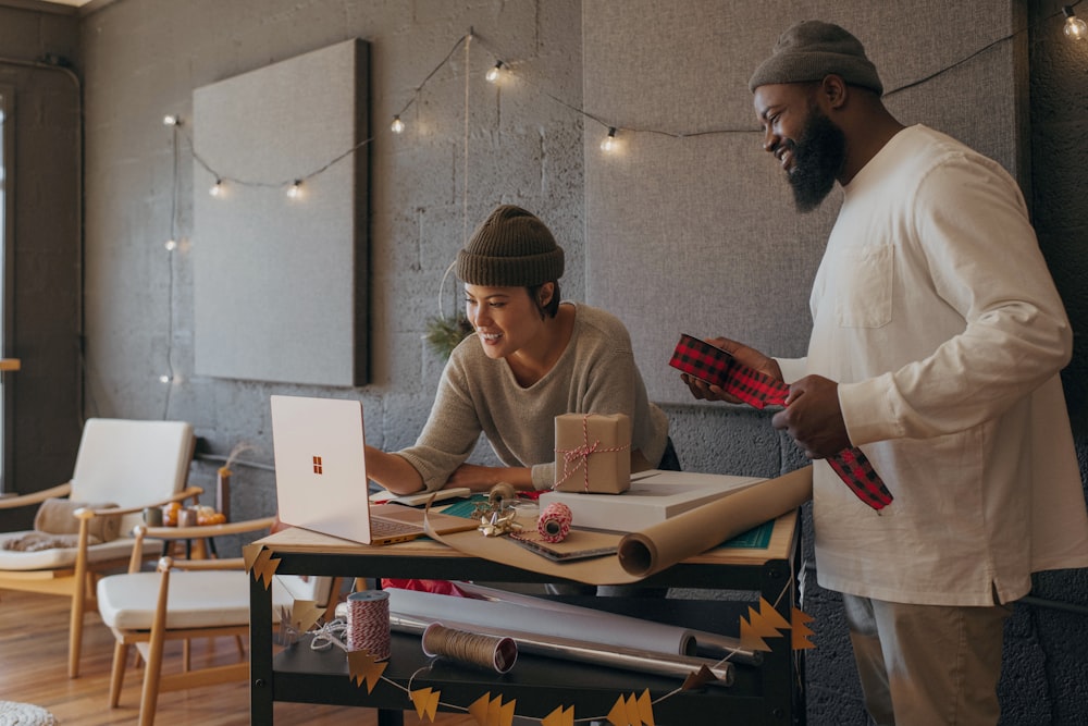 Two coworkers wrapping presents in the office while looking at a Surface laptop