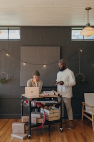 Two coworkers on a Surface laptop with Christmas presents on a cart 