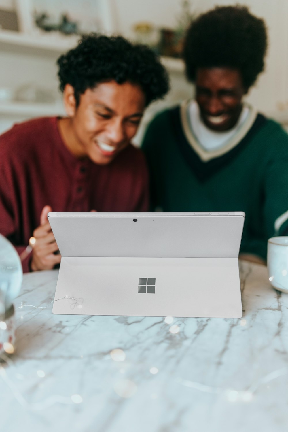 Dos personas riendo mientras miran la pantalla de una computadora portátil Surface 
