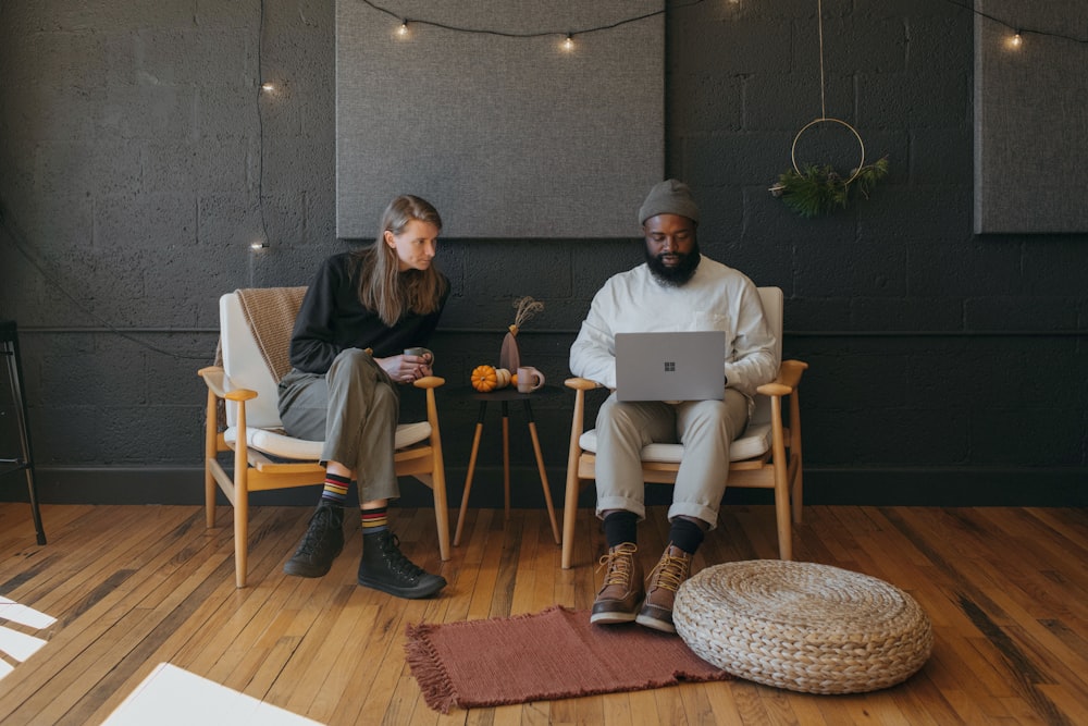 Two coworkers collaborating sitting on chairs holding a Surface laptop with Christmas decorations in the background