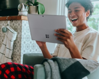 Man at home wearing pyjamas smiling at Surface Laptop screen 