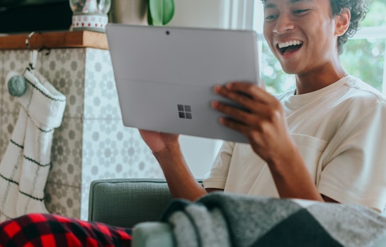 Man at home wearing pyjamas smiling at Surface Laptop screen 