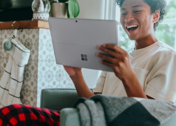 Man at home wearing pyjamas smiling at Surface Laptop screen